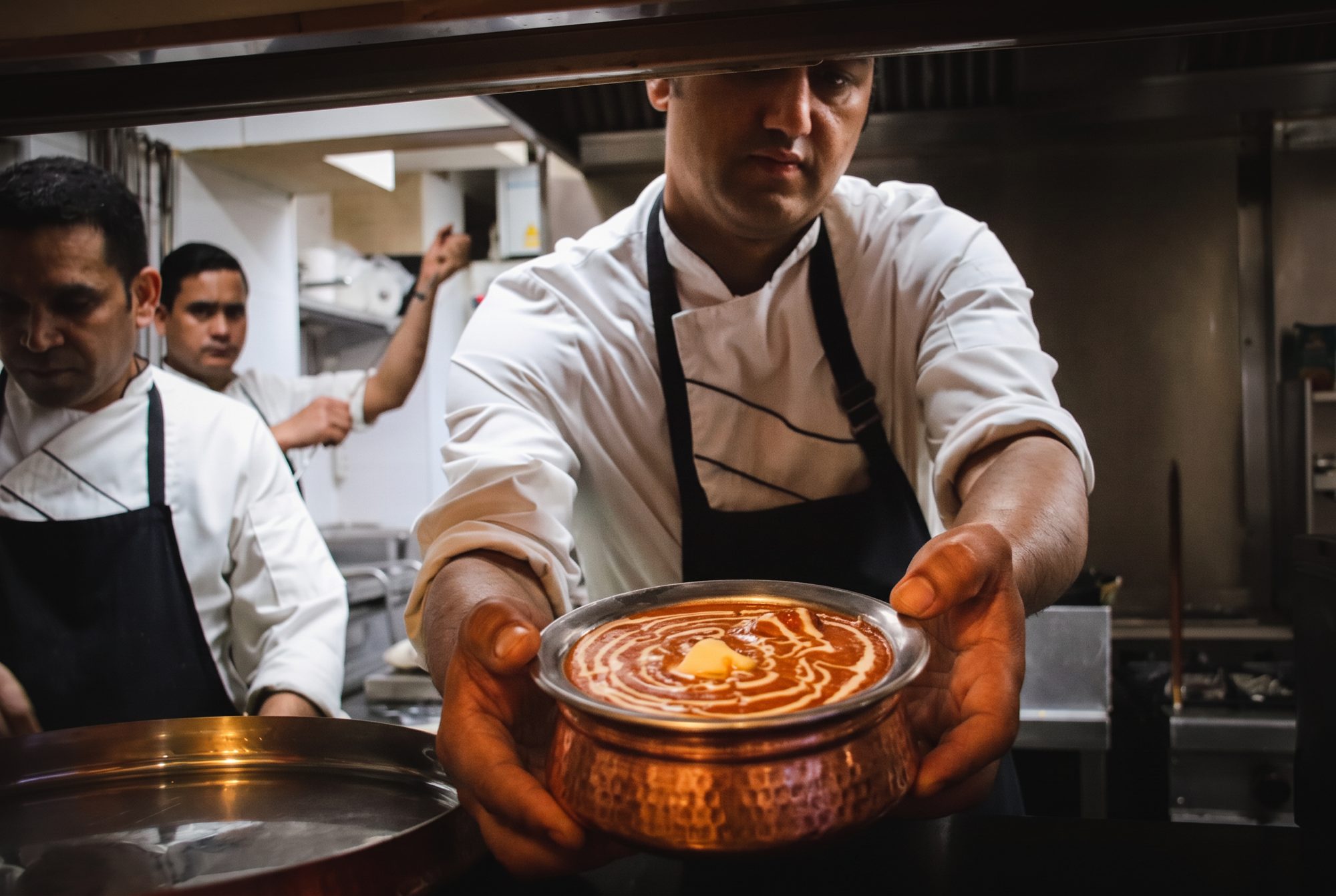 Swaagat's chef presenting butter chicken in a copper pot